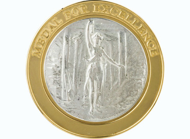 gold border to a silver centred medal, outer text reads Medal for excellence, inner shows a goddess with a lamp in a mineshaft