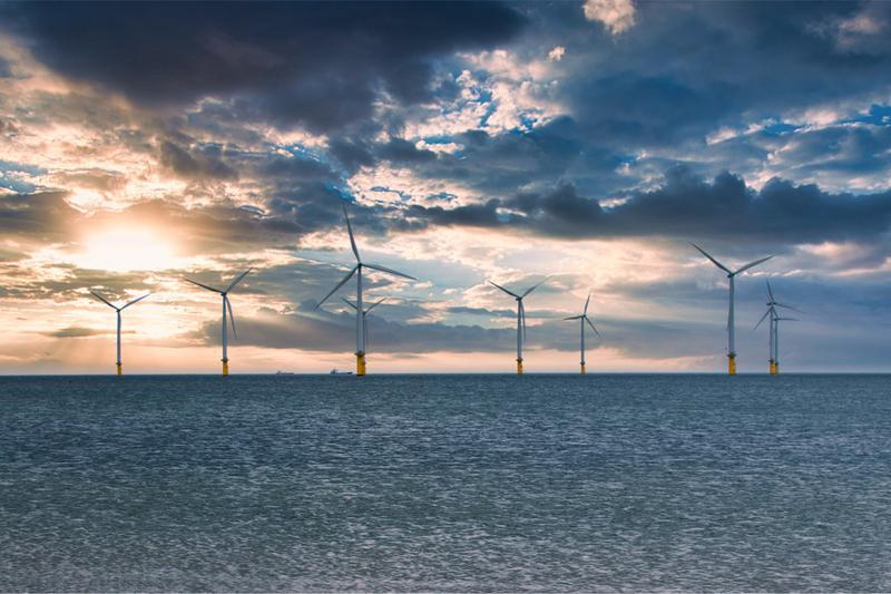 Offshore Wind Turbine in a Windfarm under construction off the England Coast at sunset