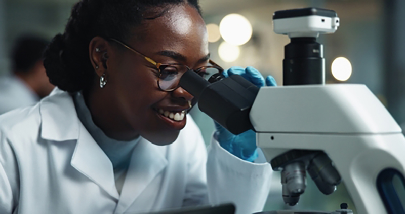 A female scientist looking through a microscope