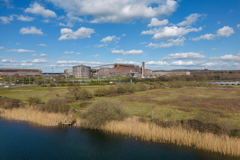river or canal at front with grassy area behind and an indistrial site to rear