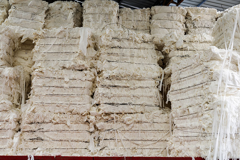 piles of white rectangular material with threads or fibres hanging off the ends