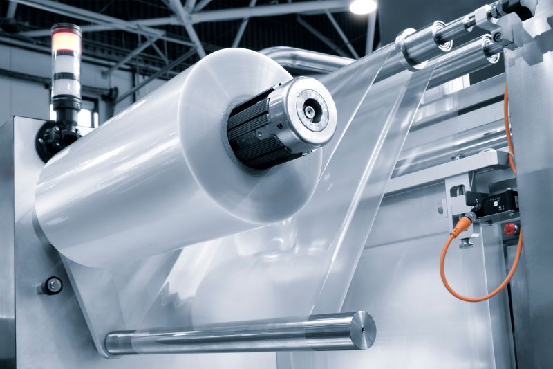 Automatic polyethylene plastic bag production machine with lighting effect. Close-up of the roller of the plastic bag production machine in the light blue scene.