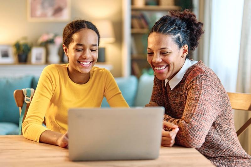 Smiling mother and daughter with laptop at home