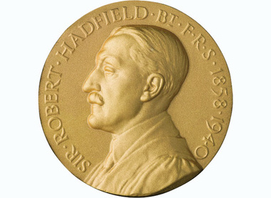 Gold circular medal with a left facing side male profile, raised lettering reads Sir Robert Hadfield Bt FRS 1858-1940 