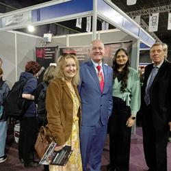 Four people (Master and Mistress Cutler with Jasneet and Peter) standing in front of the SMEA stand at the GUTS event in Sheffield.