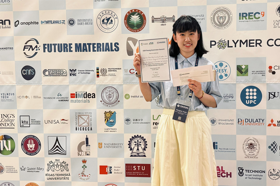 Hongna Yuan in front of the conference sponsors' logos