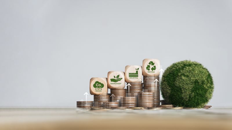 Green globe with world map and pile of silver coins growing green business concept image pictured