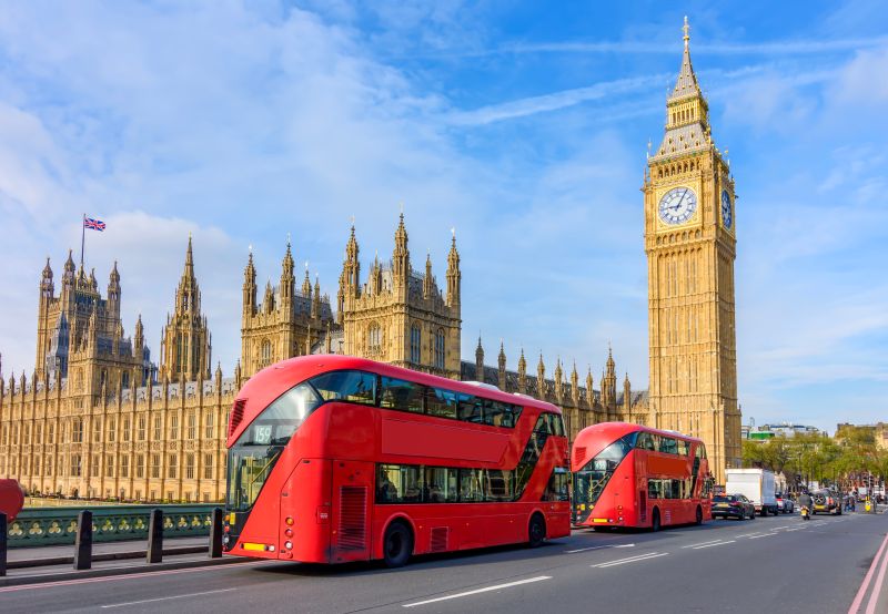 Houses of Parliament with Big Ben and double-decker buses on Westminster bridge, London, UK