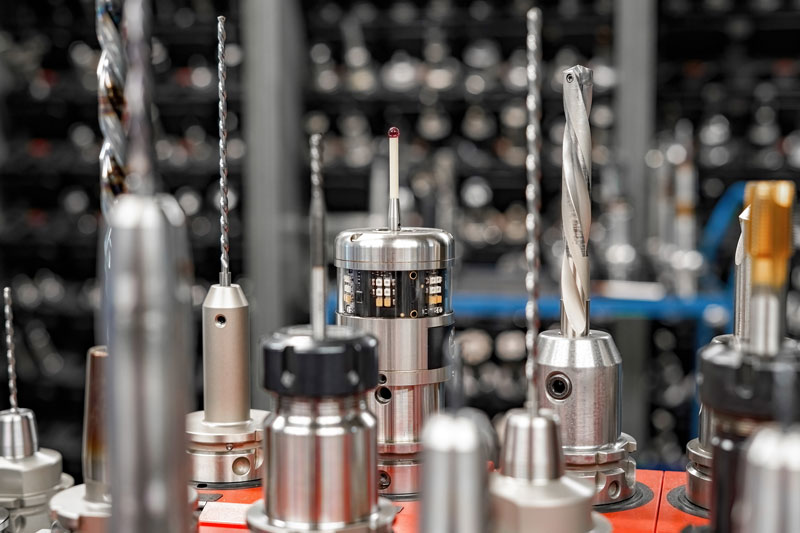Measuring tools for manufacturing lined up on a work bench, with tools in the background