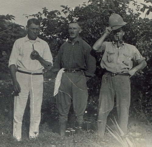 Three white men, the man on the right is dressed in white and holds a pipe, in the middle is Stephen Conrad Clavell Bate, he has a handkerchief draped from his belt. On the left the man has a hat and 