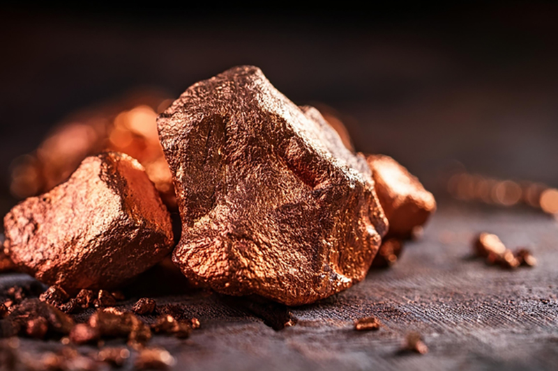 large lump of copper couloured roack with smaller pieces on a brown surface