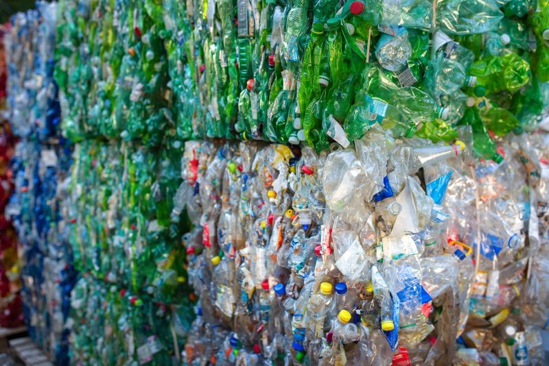 bales of plastic bottles grouped by bottle colour blue, green and clear, different colour caps are visible in each bale