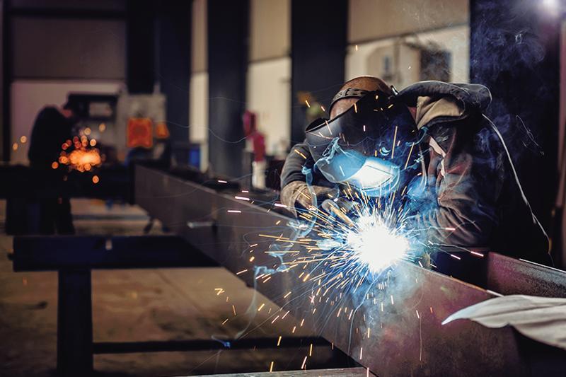 Wedler with torch and protective helmet working 