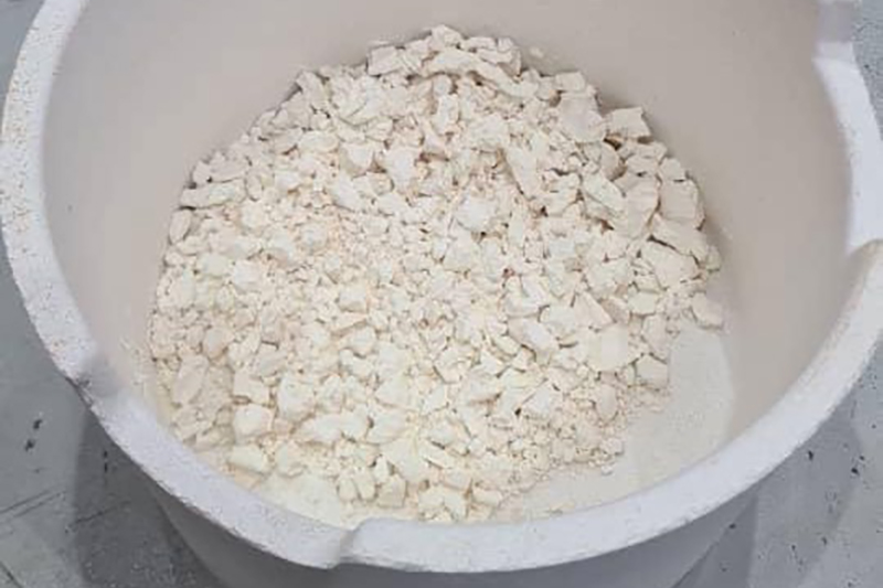 seen from above a white circular container holding a white flakey substance, some flakes are larger than others