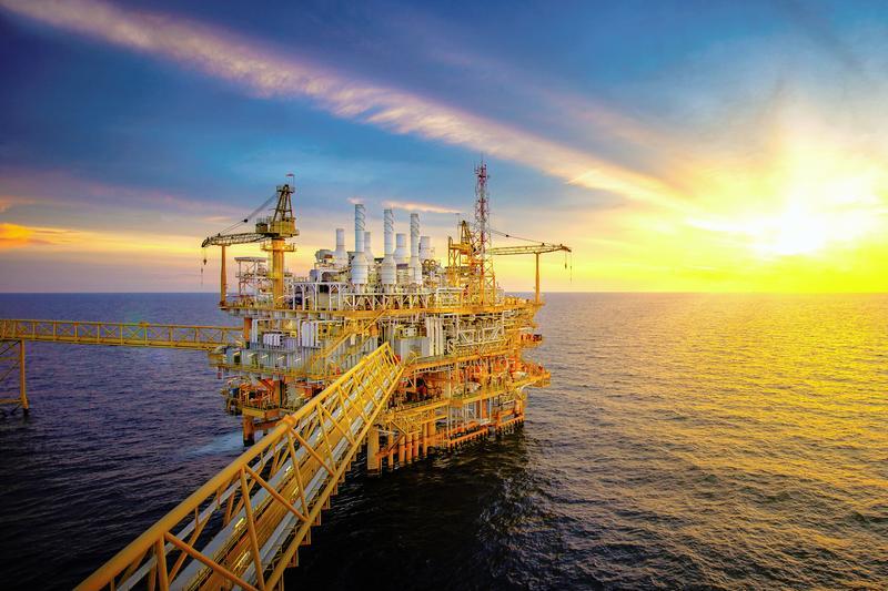 Yellow oilfield in middle of sea against backdrop of sunset