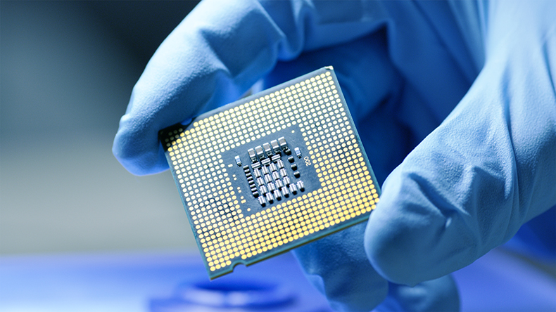 close up image of micro chip being held by a blue rubber gloved hand