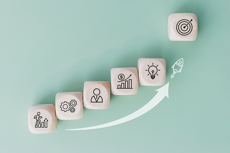 Stock graphic of rocket launching from wood cubes with business icons