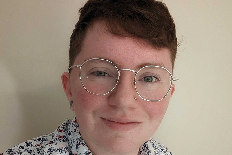 A closeup headshot of Avery Cunningham, wearing a patterned shirt and glasses