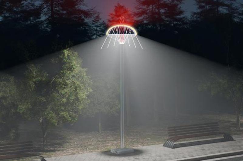pole with a net shaped top that has three red upward pointing antennas, white light is emitted illuminating a bench and pavement