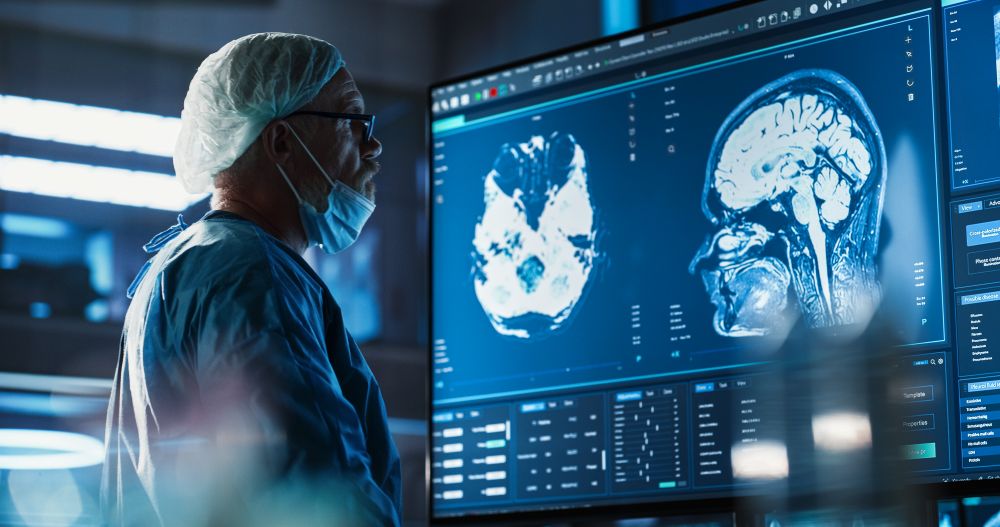 Medical Hospital Research Laboratory: Caucasian male neurosurgeon looking at TV screen with brain MRI scans of patient.