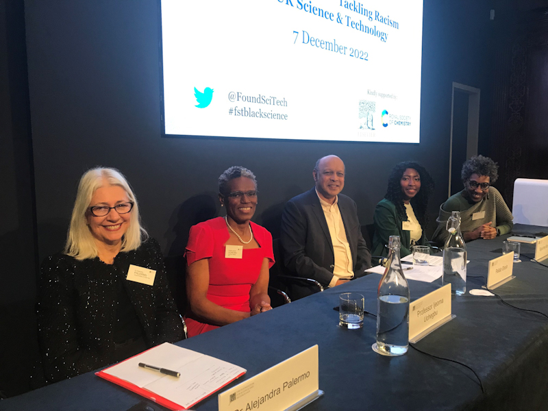 people seated at a table with name tags and microphones