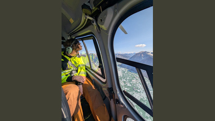 Man in looking out a helicopter in a hiviz jacket and orange trousers