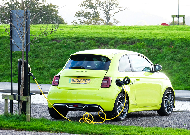 Yellow EV in an outside car park at a charging point