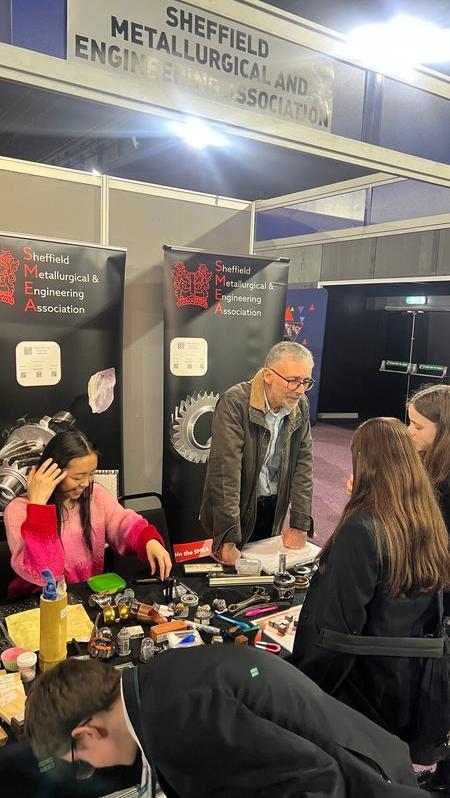 Steven and Annabel on the SMEA stand talking to students about the materials on the desk at the GUTS event in Sheffield. 
