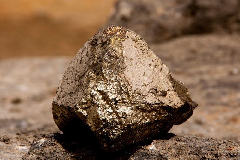 single rock of copper iron sulphide against a brown surface