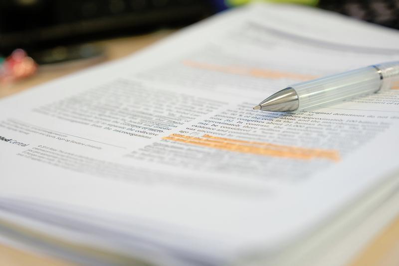 pen resting on stack of scientific papers