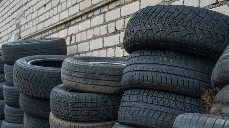 five stacks of tyres lean against a white brick wall