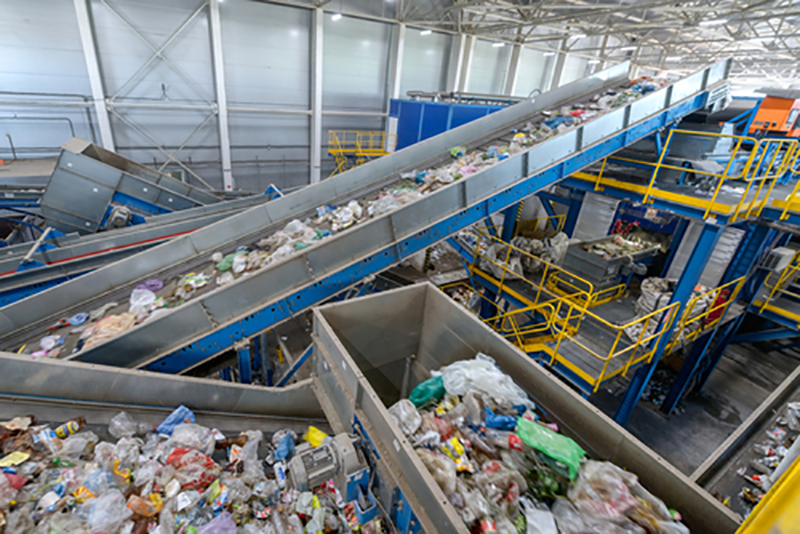 Waste sorting plant with recyclable material moving along conveyors to collection bins