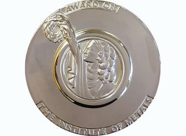 Platinum medal with text to the edge reading Award of the Institute of Metals, raised centre shows a female holding up a wreath