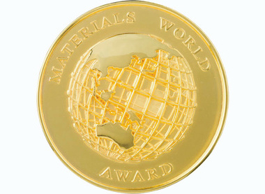 Boardered gold medal, Materials World Award appears on the boarder and a stylised globe in the centre