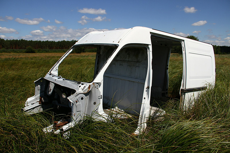 White metal parts of a van sitting in a field of long grass