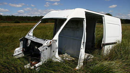 White metal parts of a van sitting in a field of long grass