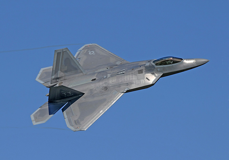Silver coloured jet against a blue sky, flying toward the upper right