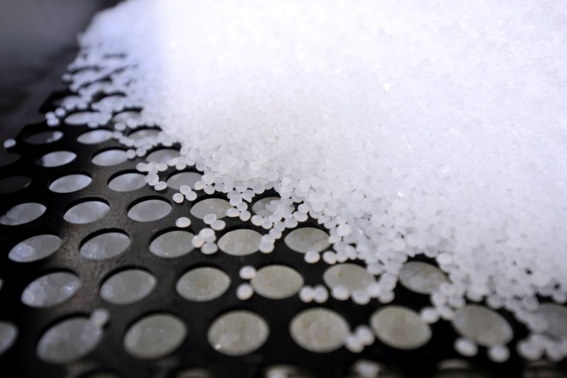 to the left a black plastic grid with circular holes is visible, tot e right it is covered with white plastic pellets