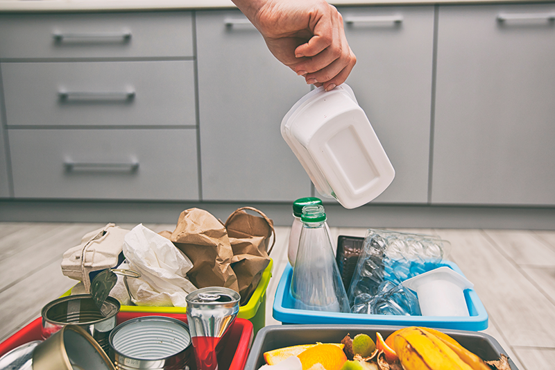 Stock image of someone sorting recycling into one of four bins at home