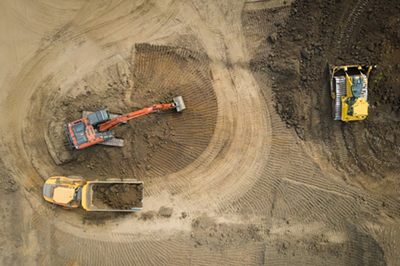 Birds-eye view of three diggers and trucks in a quarry