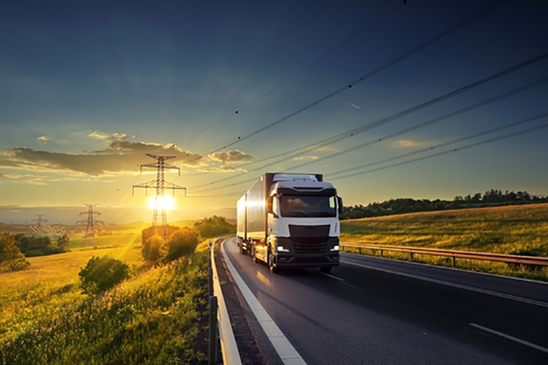 lorry on an empty road with pylons traversing countryside