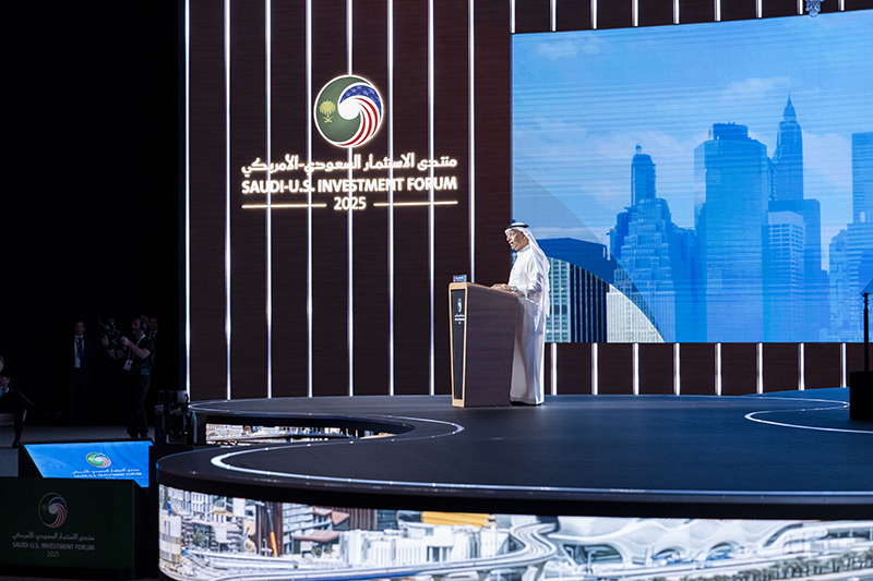 man in local dress stands at a podium in front of a backdrop for the Saudi Investment forum
