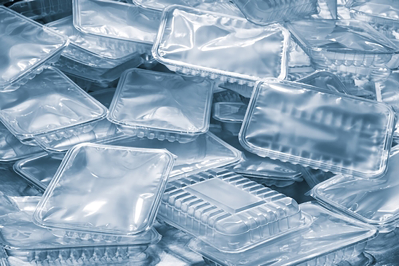 A pile of empty plastic trays with lids or with film covers, that are used as food packaging e.g. fruit punnets