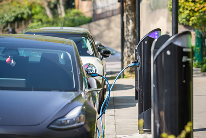 A row of parked cars using electric vehicle charging stations