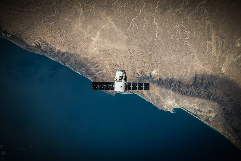 a spacecraft floats above a coastline
