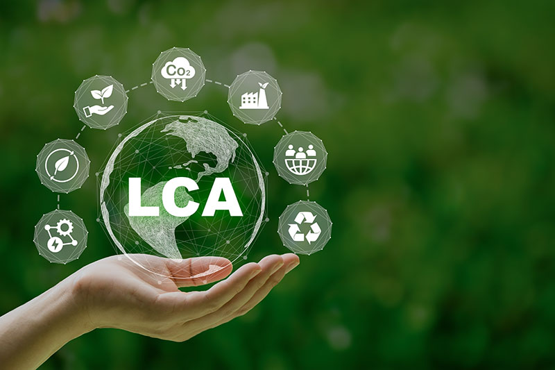 green background with a hand in front to the left, supporting bubble containing "LCA" surrounded by icons indicating sustainability factors